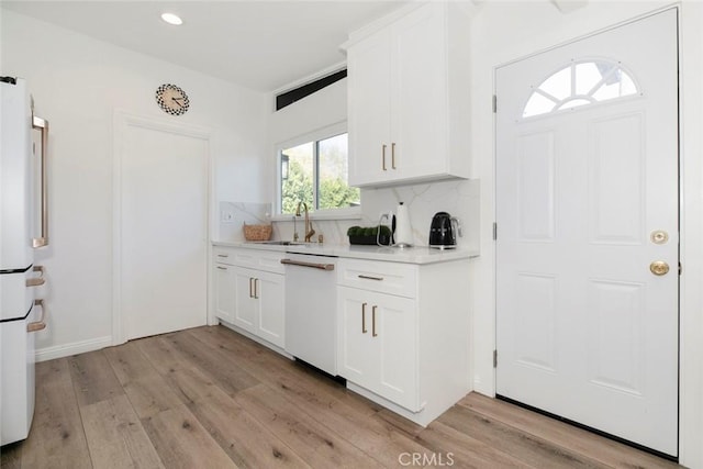 kitchen with tasteful backsplash, light hardwood / wood-style floors, sink, white appliances, and white cabinetry