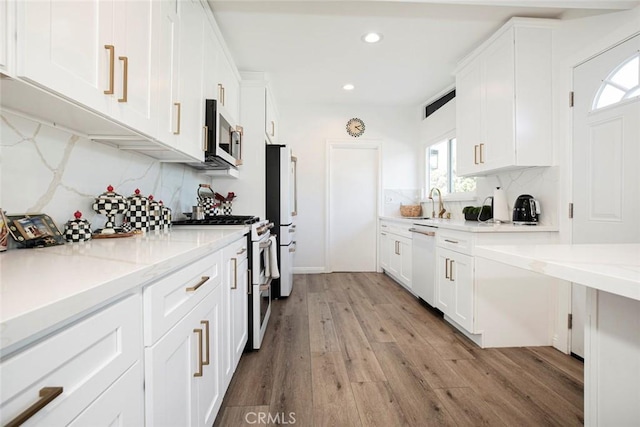 kitchen featuring decorative backsplash, white appliances, light wood-type flooring, white cabinets, and light stone counters