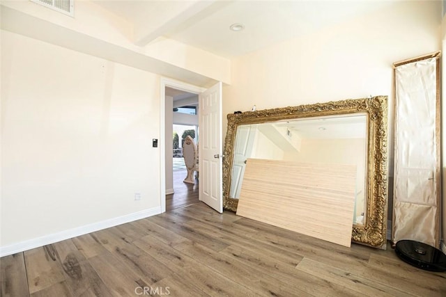 unfurnished room with hardwood / wood-style flooring and beamed ceiling