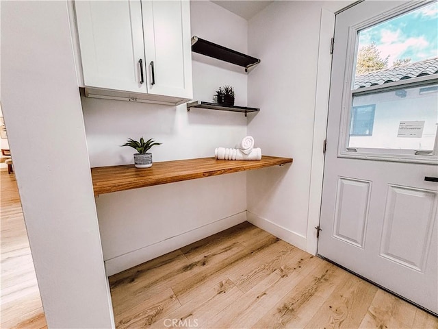 bar with light wood-type flooring, white cabinets, and wooden counters