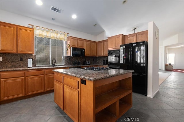 kitchen with backsplash, dark tile patterned floors, a center island, and black appliances