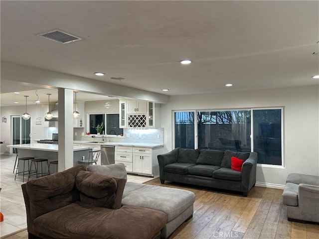 living area featuring light wood-style flooring, visible vents, baseboards, and recessed lighting