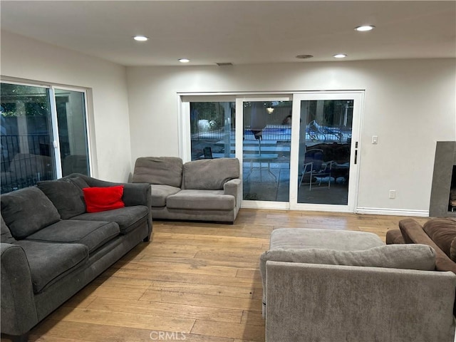 living area with light wood-type flooring, a fireplace, baseboards, and recessed lighting