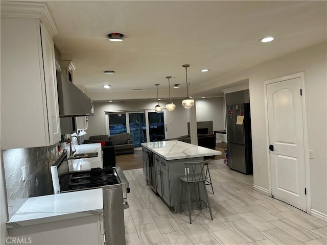 kitchen featuring a kitchen island, open floor plan, freestanding refrigerator, gray cabinets, and stainless steel range with gas cooktop