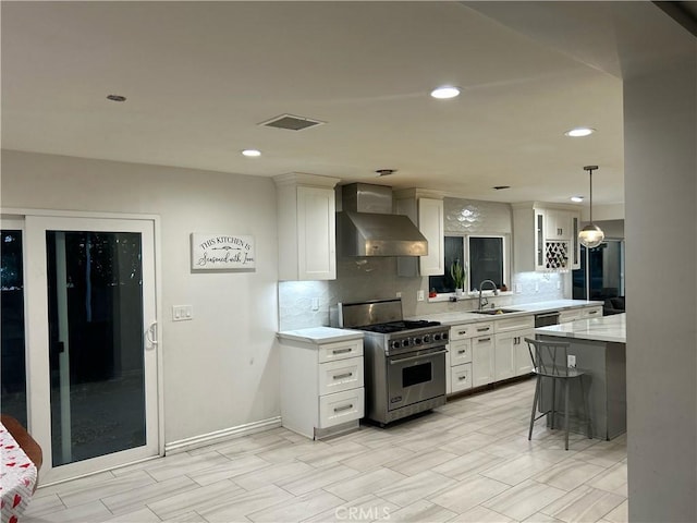 kitchen with white cabinets, wall chimney exhaust hood, designer stove, backsplash, and a sink