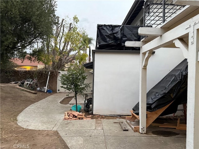 view of property exterior featuring stucco siding, fence, and a patio