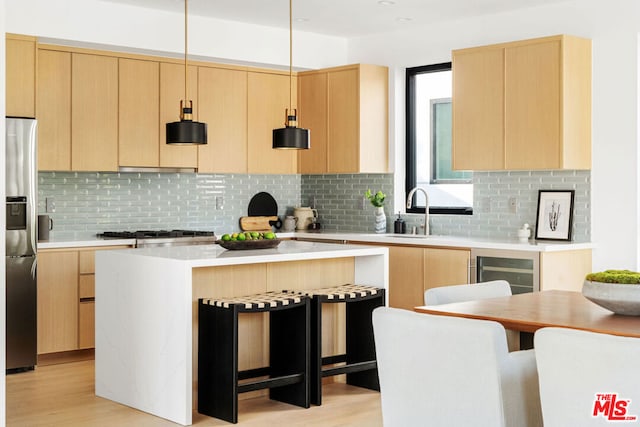 kitchen featuring appliances with stainless steel finishes, a kitchen island, decorative light fixtures, tasteful backsplash, and sink