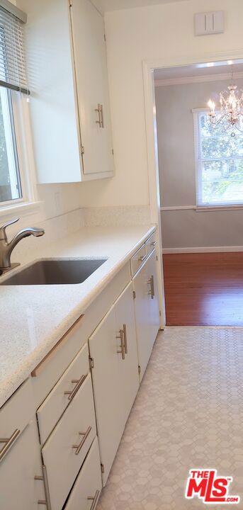 kitchen with hanging light fixtures, a chandelier, sink, and white cabinetry