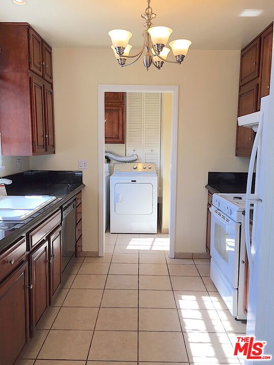 kitchen with white appliances, an inviting chandelier, sink, hanging light fixtures, and light tile patterned floors