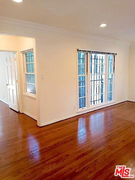 empty room with dark wood-type flooring and crown molding