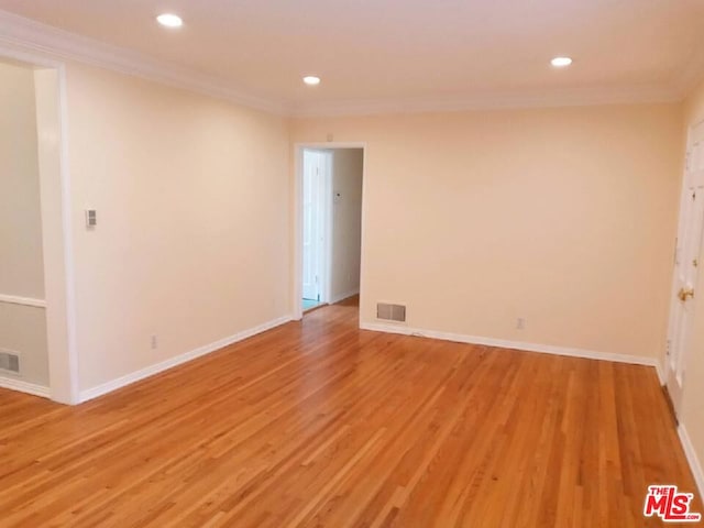 empty room with light hardwood / wood-style floors and ornamental molding