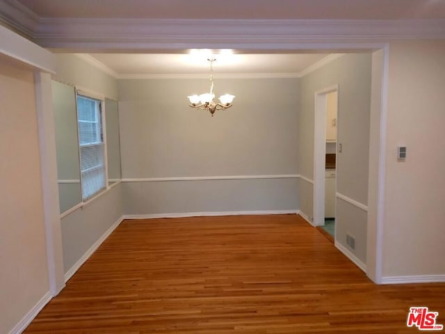 unfurnished dining area with a chandelier, crown molding, and hardwood / wood-style floors