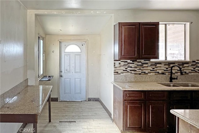 kitchen with light stone counters, sink, backsplash, and light hardwood / wood-style floors