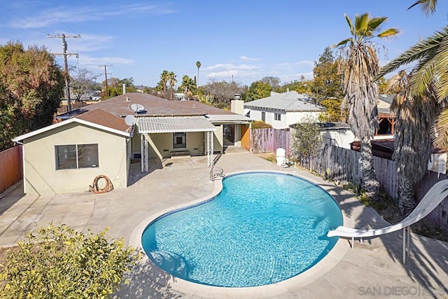 view of pool with a water slide and a patio