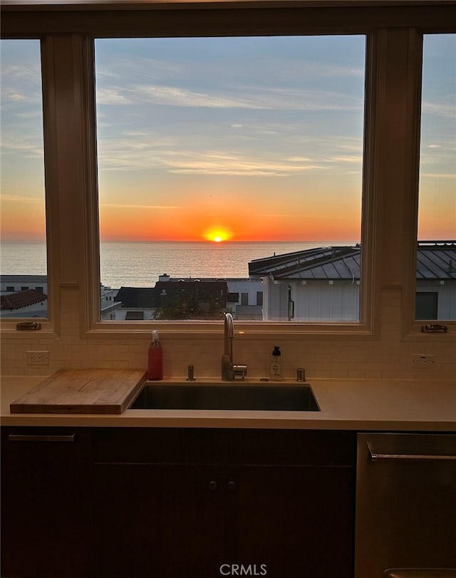 kitchen featuring dishwasher, a water view, sink, and decorative backsplash