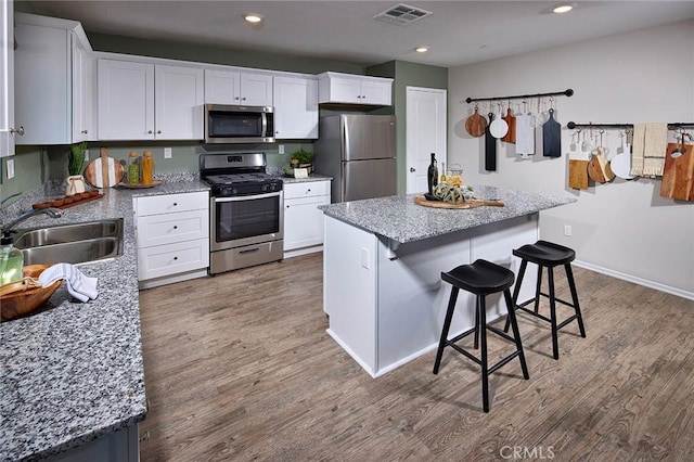 kitchen featuring white cabinets, sink, stainless steel appliances, and a center island