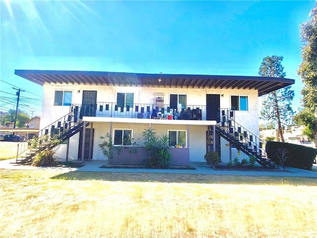 view of front facade with a front lawn and a balcony