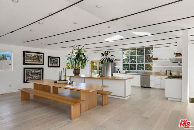 interior space with white cabinetry, appliances with stainless steel finishes, range hood, light hardwood / wood-style flooring, and sink