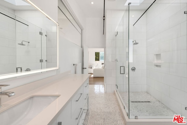 bathroom featuring a skylight, tile patterned flooring, an enclosed shower, and vanity