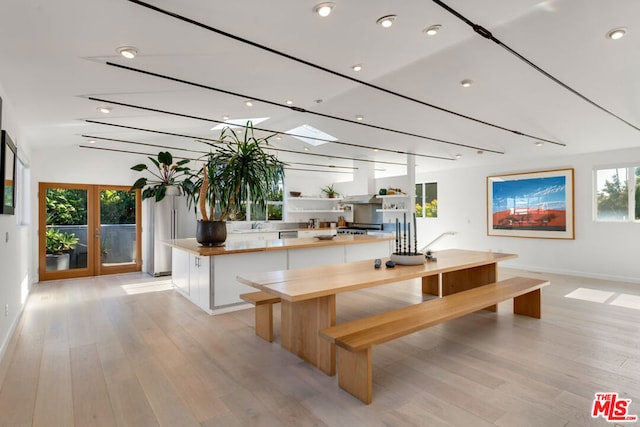 interior space featuring a skylight, white cabinetry, light wood-type flooring, french doors, and a kitchen island