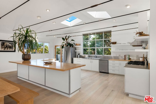 kitchen with sink, light hardwood / wood-style flooring, a skylight, appliances with stainless steel finishes, and white cabinets