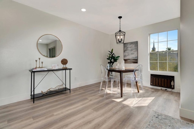 dining room with heating unit, light wood-type flooring, and an inviting chandelier