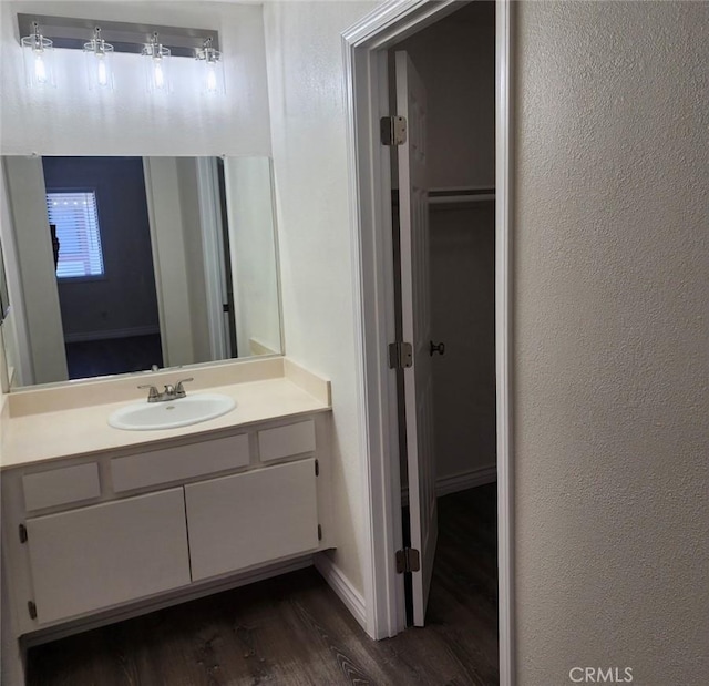 bathroom with baseboards, a textured wall, wood finished floors, and vanity