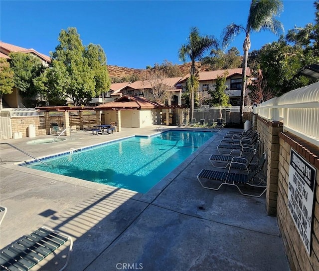 community pool with fence and a patio area