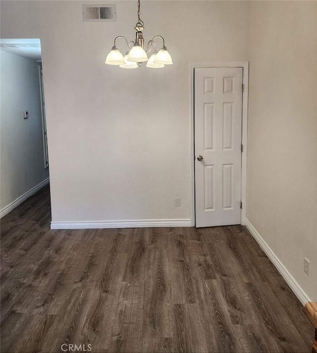 unfurnished dining area featuring dark wood-type flooring and a notable chandelier