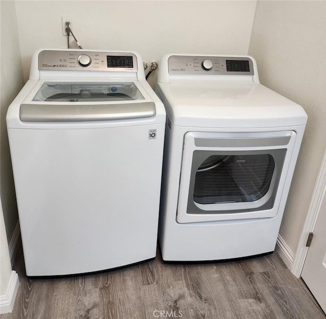 clothes washing area featuring wood-type flooring and washing machine and clothes dryer