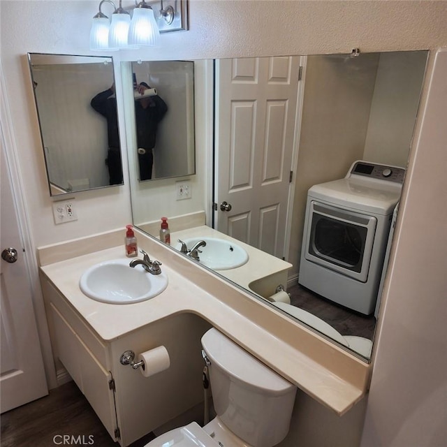 bathroom featuring toilet, vanity, wood finished floors, washer / dryer, and a textured wall