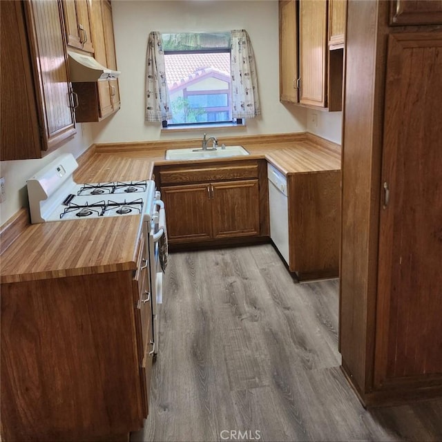 kitchen featuring a sink, butcher block counters, light wood-style flooring, under cabinet range hood, and gas stove