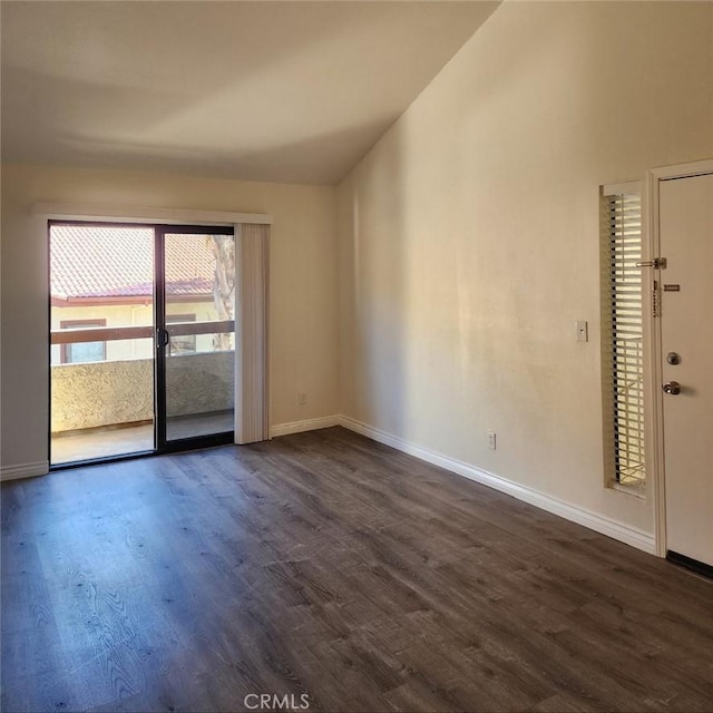 spare room featuring baseboards, lofted ceiling, and dark wood-type flooring
