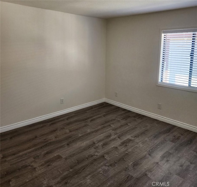 empty room with baseboards and dark wood-type flooring