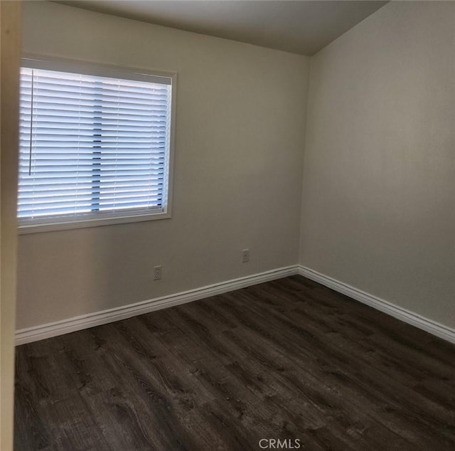 spare room featuring dark wood-style flooring and baseboards