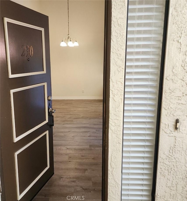 hall featuring dark wood-type flooring and an inviting chandelier