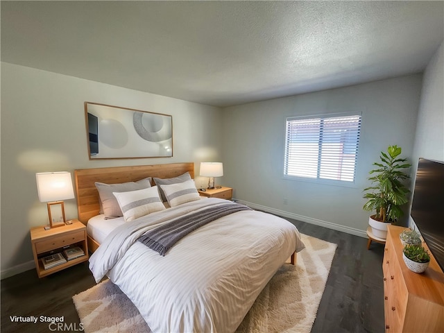 bedroom featuring baseboards, wood finished floors, and a textured ceiling