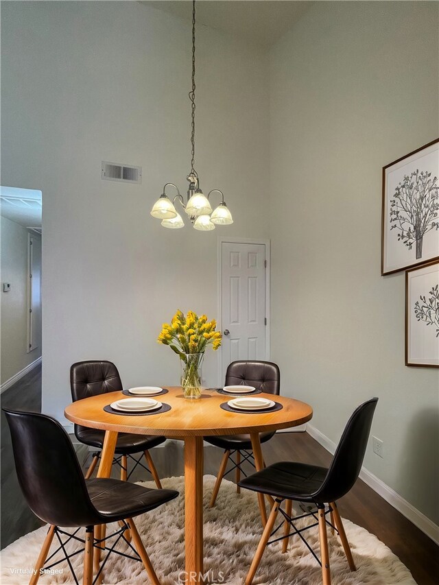 dining space featuring dark hardwood / wood-style flooring, a towering ceiling, and a notable chandelier