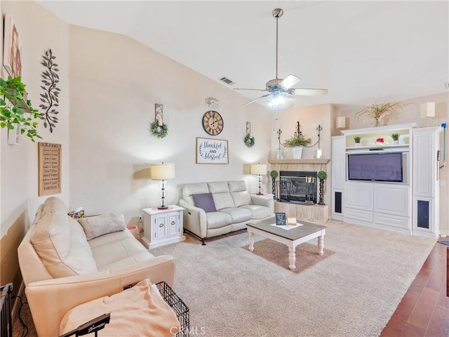 living room featuring vaulted ceiling, ceiling fan, wood-type flooring, and a tiled fireplace