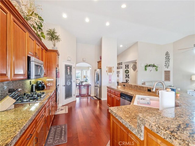 kitchen with light stone counters, sink, backsplash, and appliances with stainless steel finishes