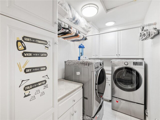 laundry room with light tile patterned floors, washing machine and dryer, and cabinets