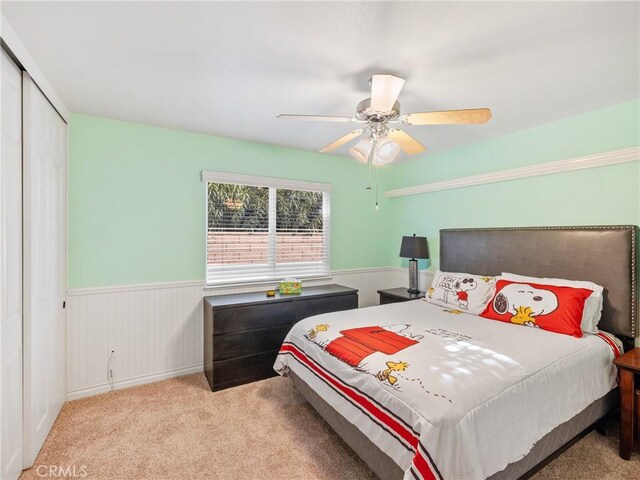 bedroom with ceiling fan, a closet, and light colored carpet