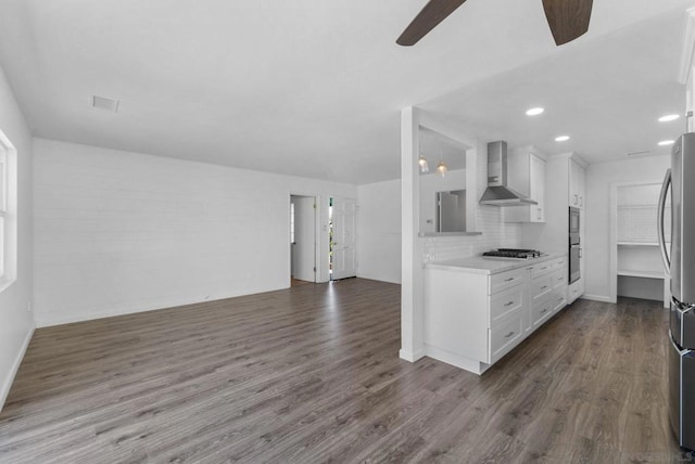 kitchen featuring appliances with stainless steel finishes, wall chimney exhaust hood, decorative backsplash, and white cabinetry