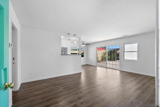 unfurnished living room with ceiling fan and dark wood-type flooring