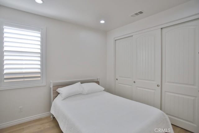 bedroom featuring multiple windows, a closet, and light wood-type flooring