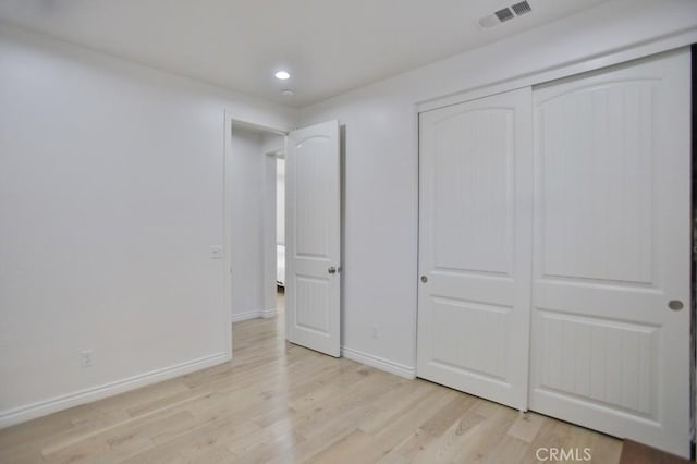 unfurnished bedroom with light wood-type flooring and a closet