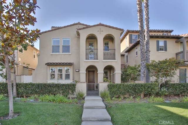 mediterranean / spanish home featuring a balcony and a front lawn