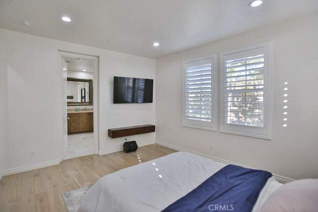 bedroom with ensuite bath and light wood-type flooring