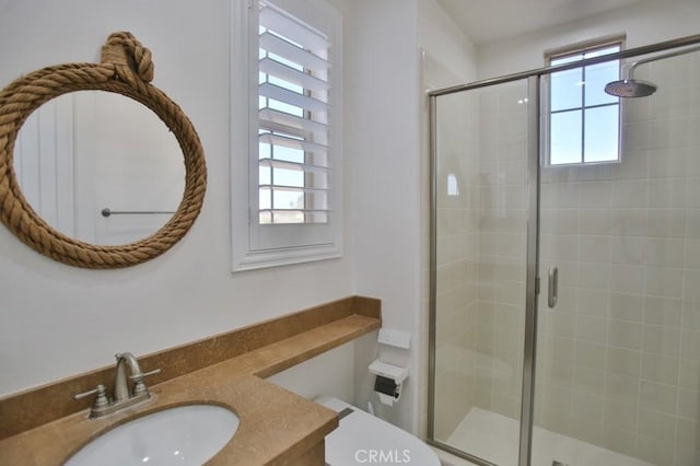 bathroom with toilet, a shower with shower door, and vanity