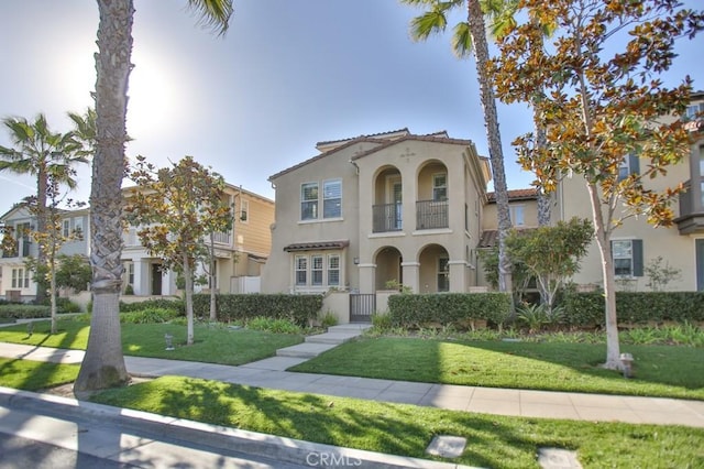 mediterranean / spanish-style house featuring a balcony and a front yard